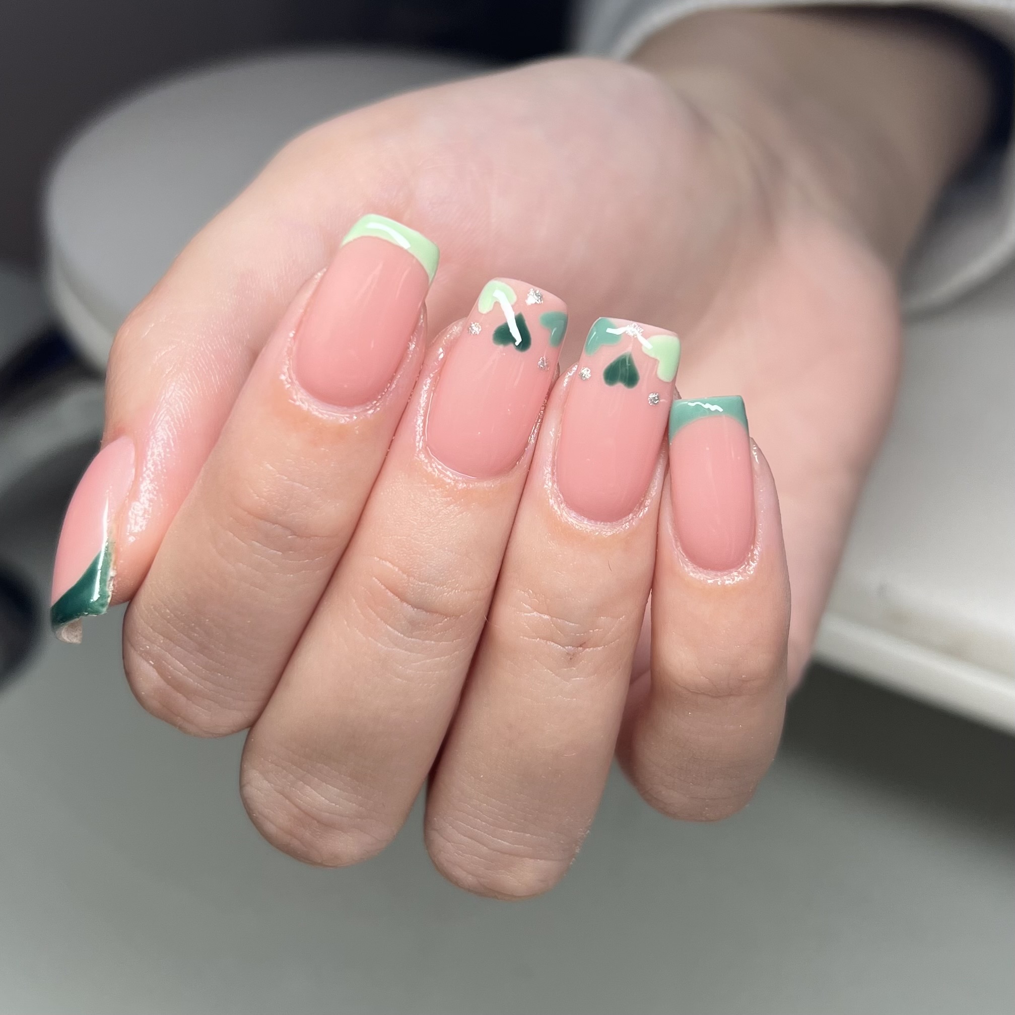 Nude nails with mint and green French tips and hearts
