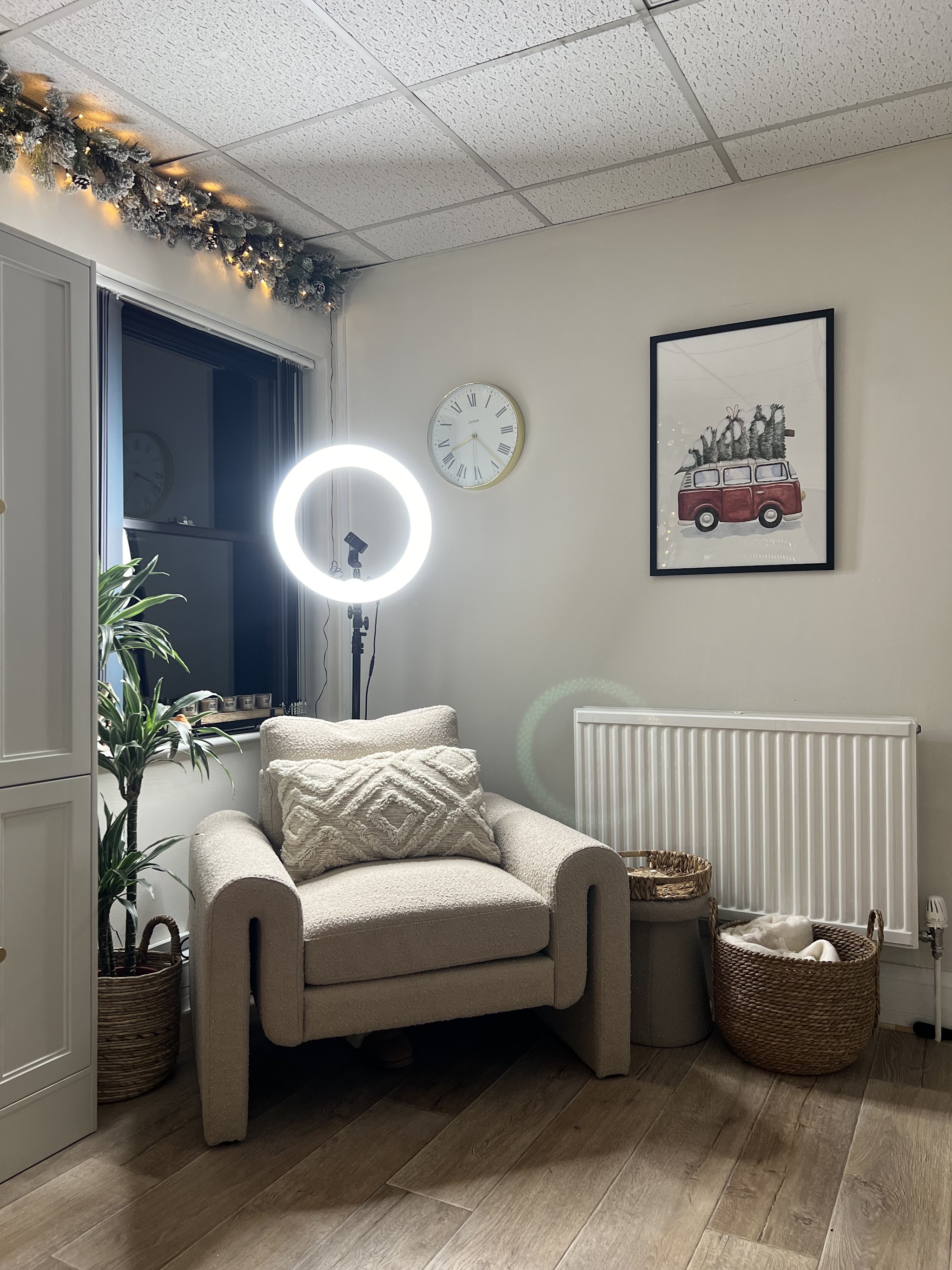A cosy corner of the studio with a cream armchair, ring light and a framed campervan print
